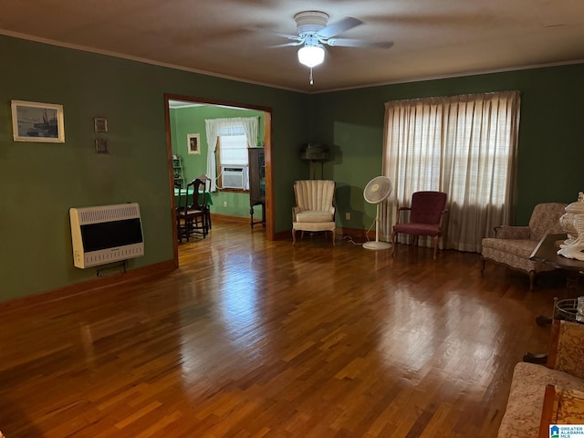 living area featuring heating unit, ceiling fan, ornamental molding, and wood finished floors