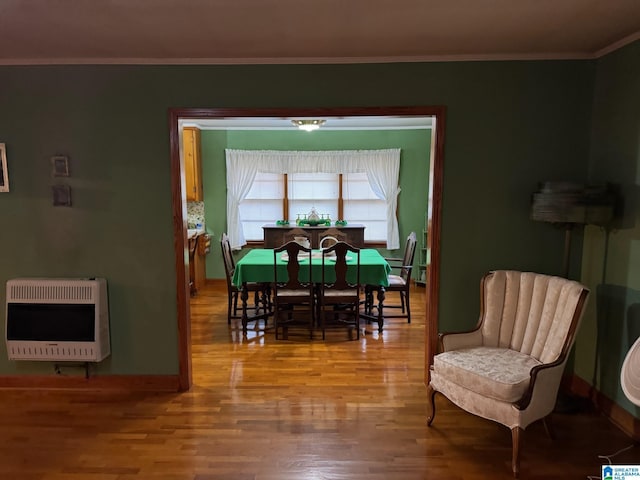 dining area featuring crown molding, baseboards, wood finished floors, and heating unit