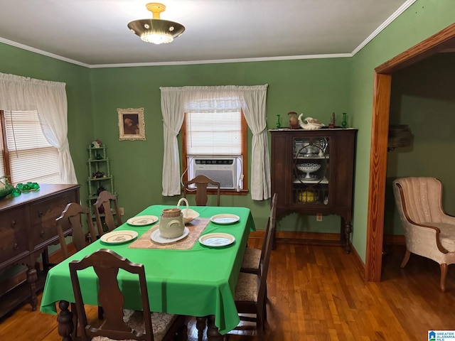 dining room featuring baseboards, cooling unit, ornamental molding, and wood finished floors