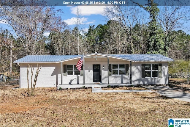 view of front of property with metal roof, brick siding, and fence