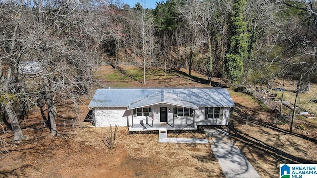 view of front of house with metal roof and a view of trees