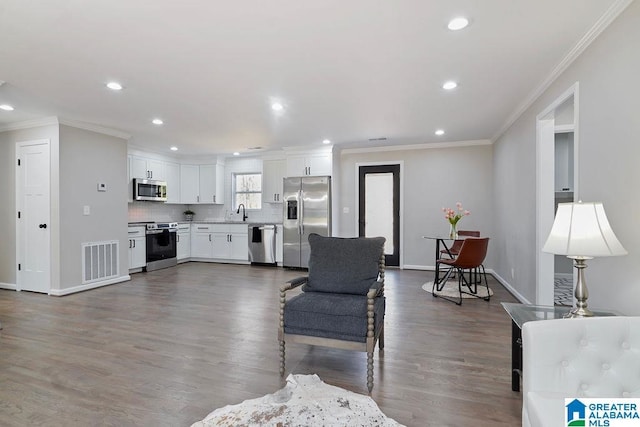 living area featuring baseboards, visible vents, dark wood-style flooring, crown molding, and recessed lighting