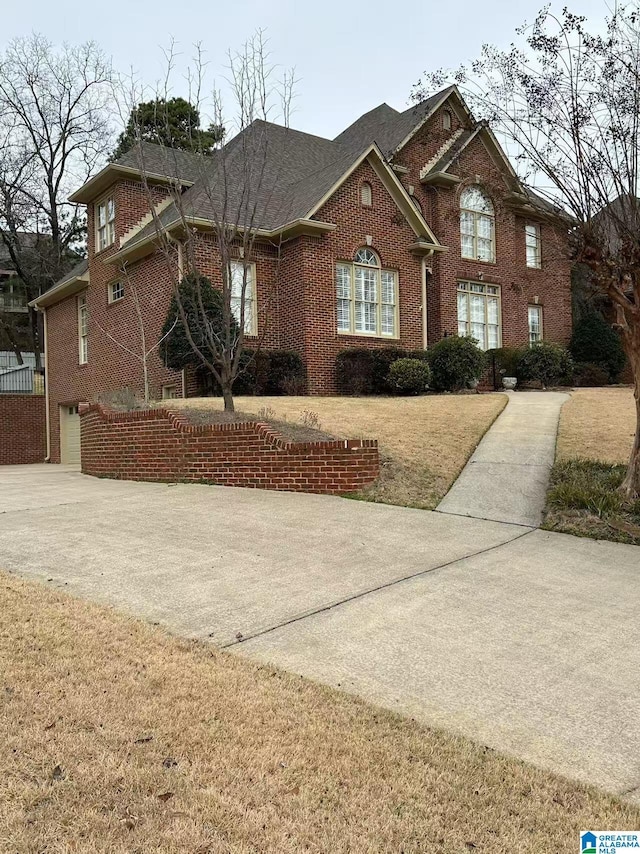 view of front of house with concrete driveway, brick siding, and a front lawn