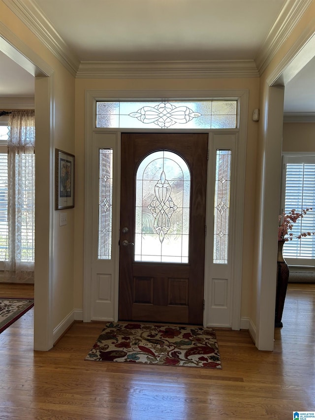 foyer entrance with ornamental molding, a wealth of natural light, and wood finished floors