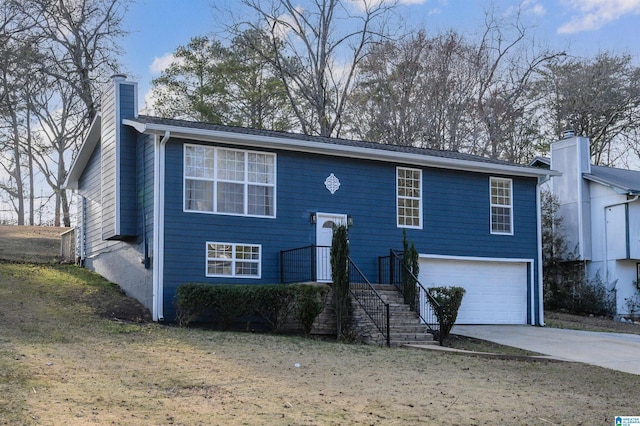 bi-level home featuring a garage, a chimney, and concrete driveway