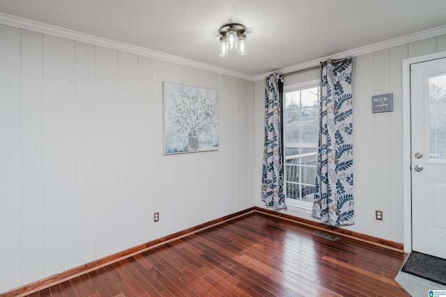 spare room with visible vents, crown molding, baseboards, and wood finished floors