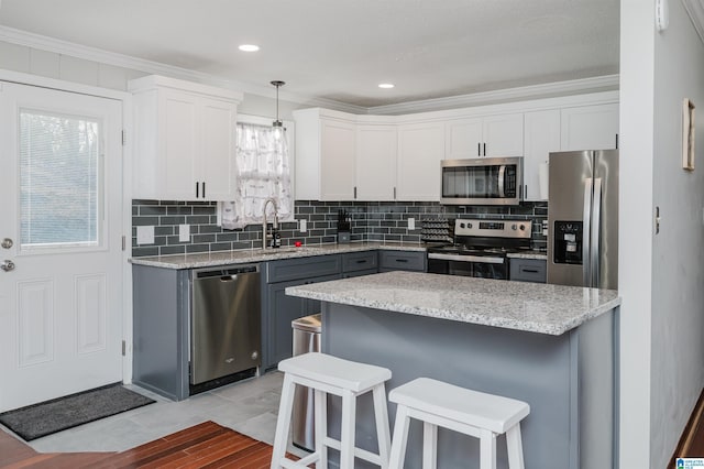 kitchen with stainless steel appliances, a sink, a kitchen breakfast bar, backsplash, and crown molding