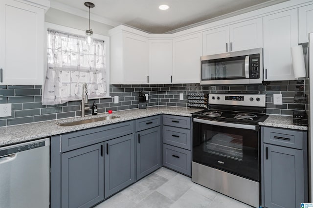 kitchen with stainless steel appliances, a sink, white cabinets, tasteful backsplash, and pendant lighting