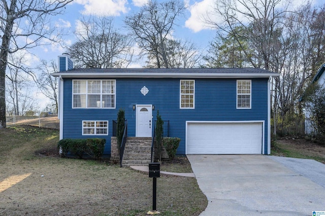 split foyer home with a garage, concrete driveway, and a chimney