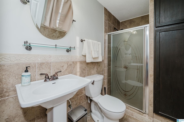 full bath with toilet, a shower stall, tile walls, and wainscoting