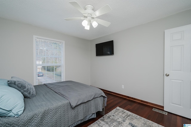 bedroom featuring dark wood-style floors, visible vents, a textured ceiling, and baseboards