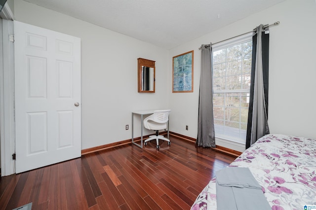 bedroom featuring a textured ceiling, baseboards, and wood finished floors