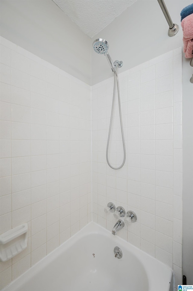 bathroom with a textured ceiling and shower / tub combination