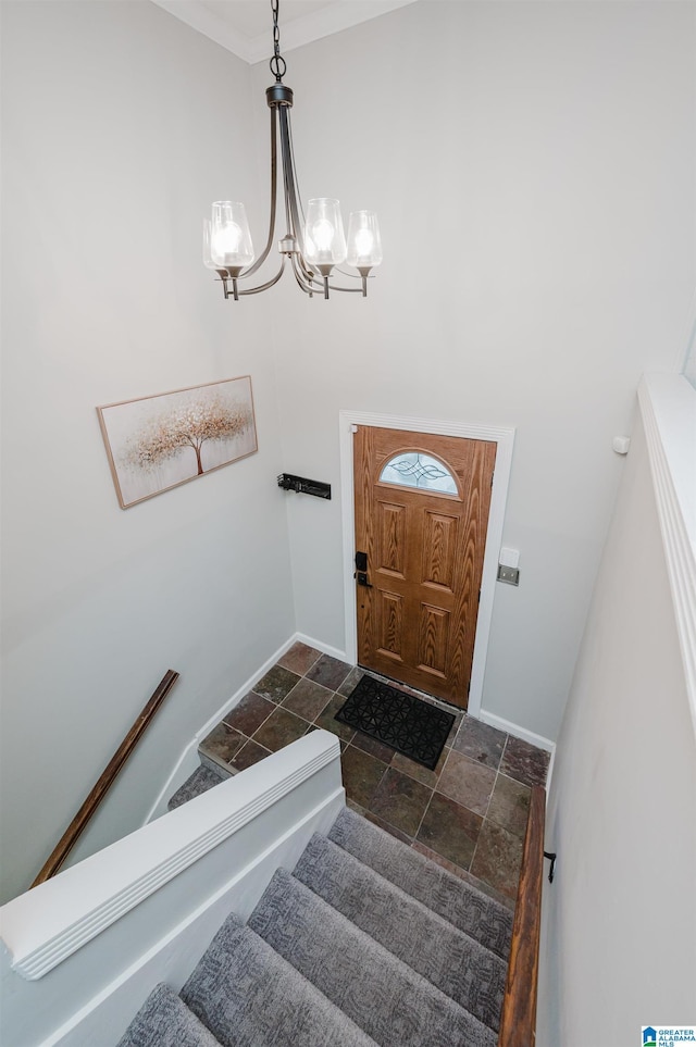 entrance foyer with baseboards, stairway, an inviting chandelier, and stone tile floors