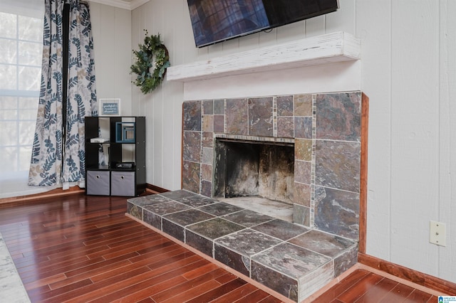 details with baseboards, a tiled fireplace, and wood finished floors