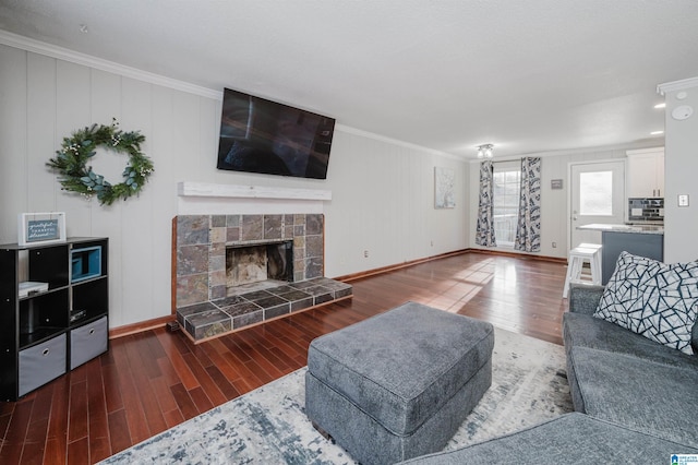 living room with baseboards, ornamental molding, wood finished floors, and a tile fireplace