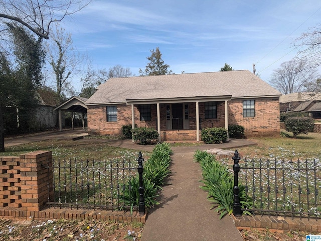 back of house featuring covered porch, brick siding, a fenced front yard, and an attached carport