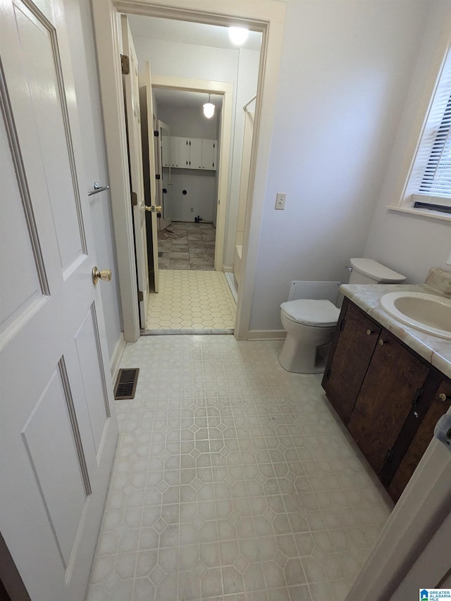 full bath featuring toilet, vanity, visible vents, baseboards, and a stall shower