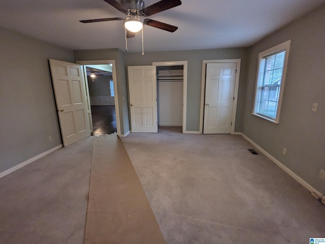 unfurnished bedroom with light carpet, a ceiling fan, visible vents, and baseboards