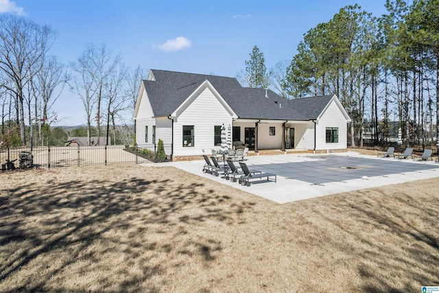 rear view of house with a shingled roof, a patio area, fence, and a fenced in pool