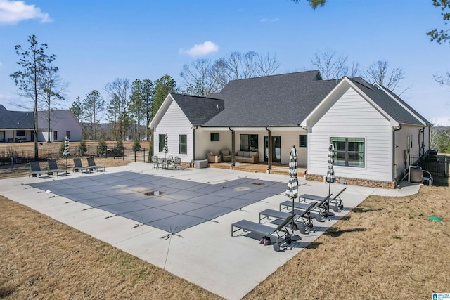 rear view of property featuring a fenced in pool, roof with shingles, fence, and a patio