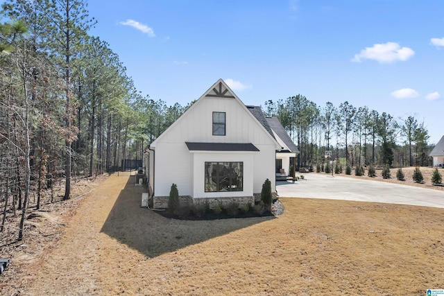 view of side of home with a patio area, a shingled roof, and concrete driveway