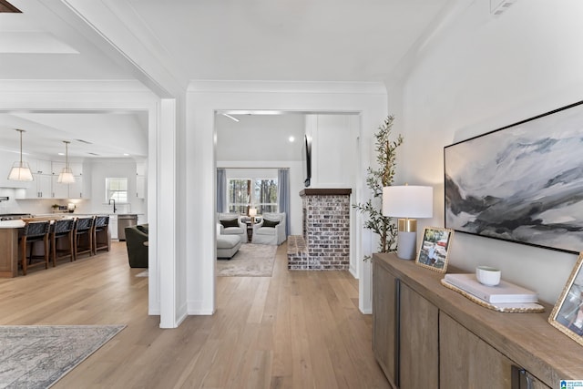 hallway with ornamental molding, plenty of natural light, and light wood-style flooring