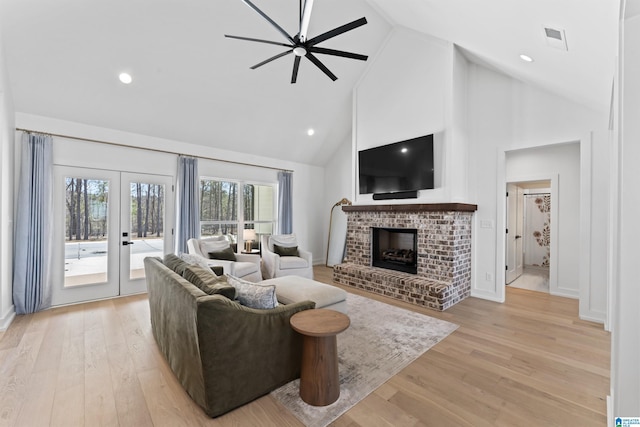 living room with ceiling fan, french doors, a fireplace, and light wood-style flooring