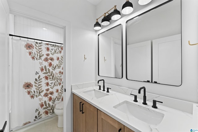 bathroom featuring toilet, double vanity, a sink, and a shower with shower curtain