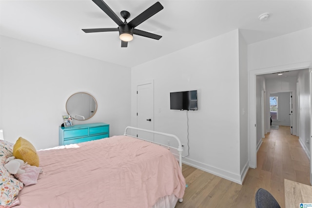 bedroom featuring light wood-style flooring, baseboards, and a ceiling fan