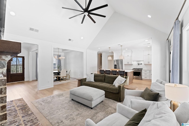 living area featuring recessed lighting, visible vents, light wood-style floors, high vaulted ceiling, and baseboards