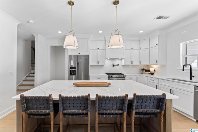 kitchen featuring appliances with stainless steel finishes, a sink, white cabinets, and decorative backsplash