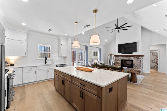 kitchen with stainless steel range, a sink, visible vents, and white cabinets