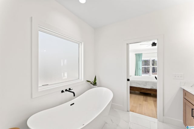 full bath featuring baseboards, connected bathroom, a soaking tub, marble finish floor, and vanity