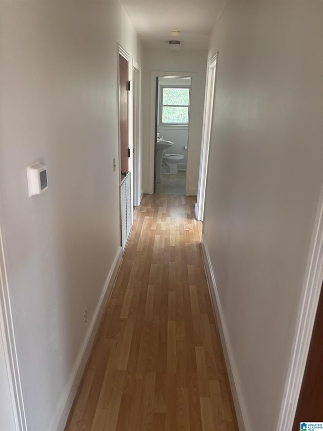 corridor featuring light wood-type flooring and baseboards