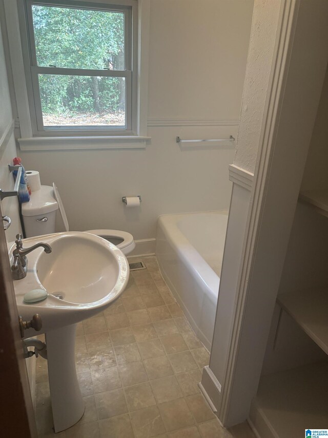 bathroom featuring a tub, a sink, and toilet