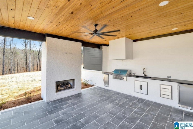 view of patio with area for grilling, a sink, exterior kitchen, a fireplace, and ceiling fan