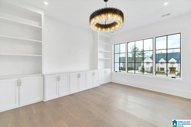 spare room with built in features, visible vents, light wood-style floors, and recessed lighting