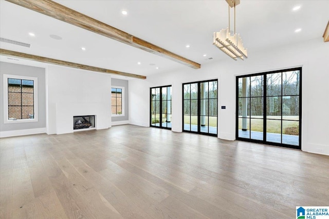 unfurnished living room with beamed ceiling, visible vents, light wood-style flooring, a fireplace, and baseboards