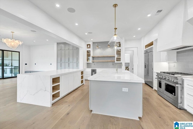 kitchen with visible vents, a large island, high quality appliances, custom range hood, and open shelves