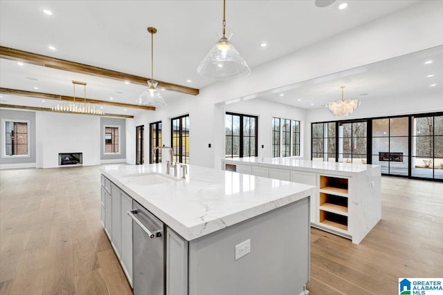 kitchen featuring a center island with sink, open shelves, a sink, stainless steel dishwasher, and open floor plan