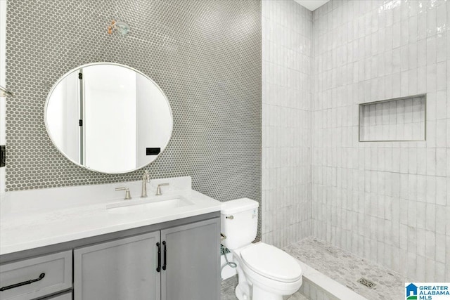 bathroom featuring a tile shower, toilet, and vanity