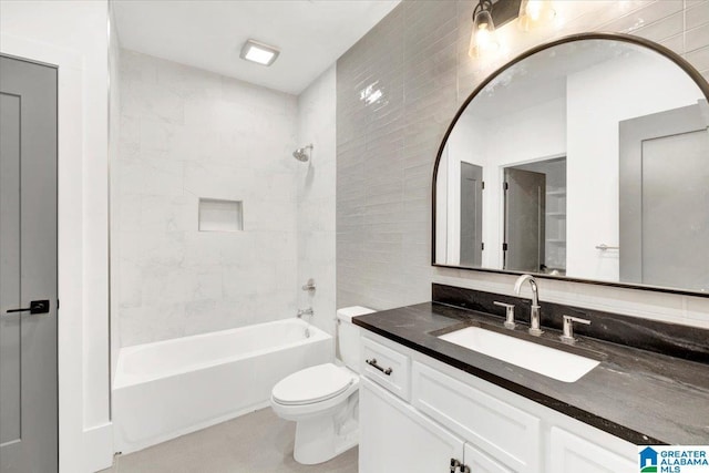 bathroom with vanity, toilet, tile walls, and  shower combination