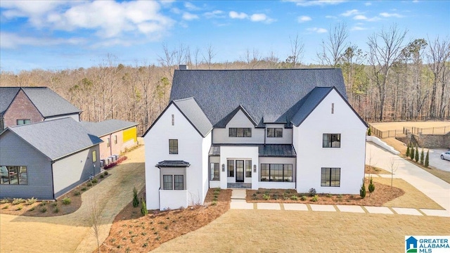 modern inspired farmhouse featuring a chimney, a forest view, a standing seam roof, and metal roof