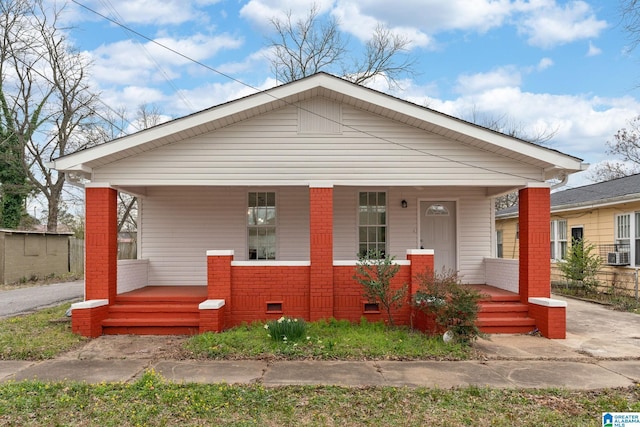 view of front facade with crawl space, a porch, cooling unit, and brick siding