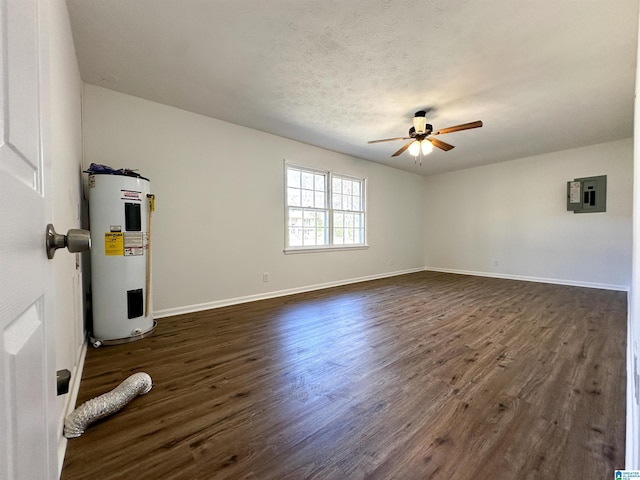 spare room with water heater, ceiling fan, dark wood-type flooring, and electric panel