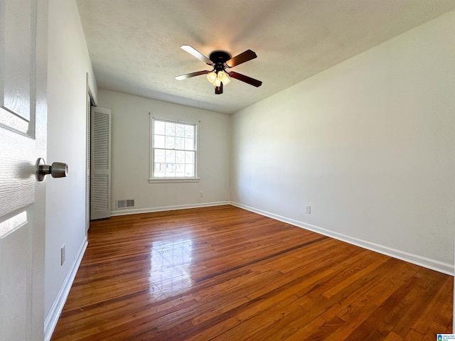 unfurnished room featuring visible vents, a ceiling fan, baseboards, and hardwood / wood-style flooring