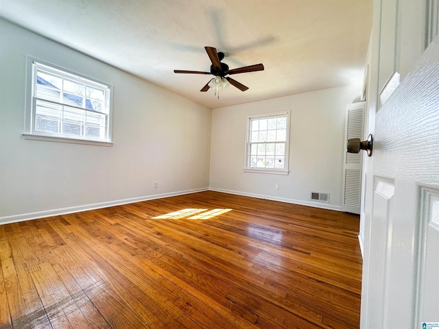 unfurnished room with visible vents, baseboards, and hardwood / wood-style flooring