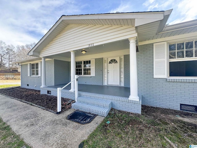 view of front of home with crawl space, a porch, and brick siding