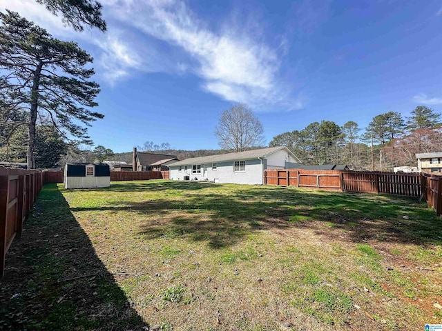 view of yard with a fenced backyard, a storage unit, and an outdoor structure